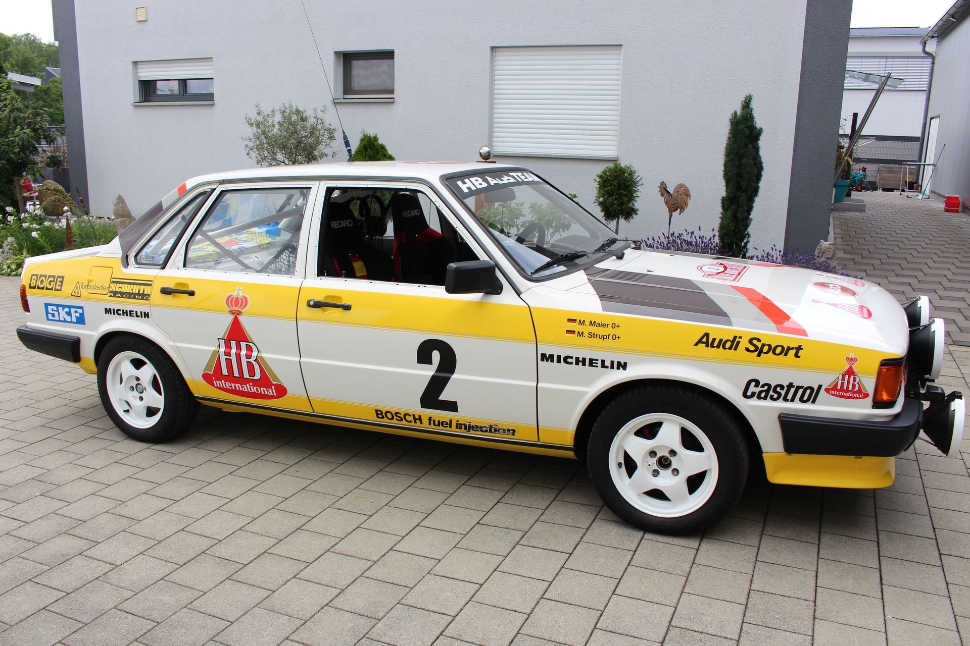 Weiß-gelber Audi Sport Rennwagen mit der Nummer 2, Sponsorenlogos von HB International, Castrol, Michelin und Bosch.