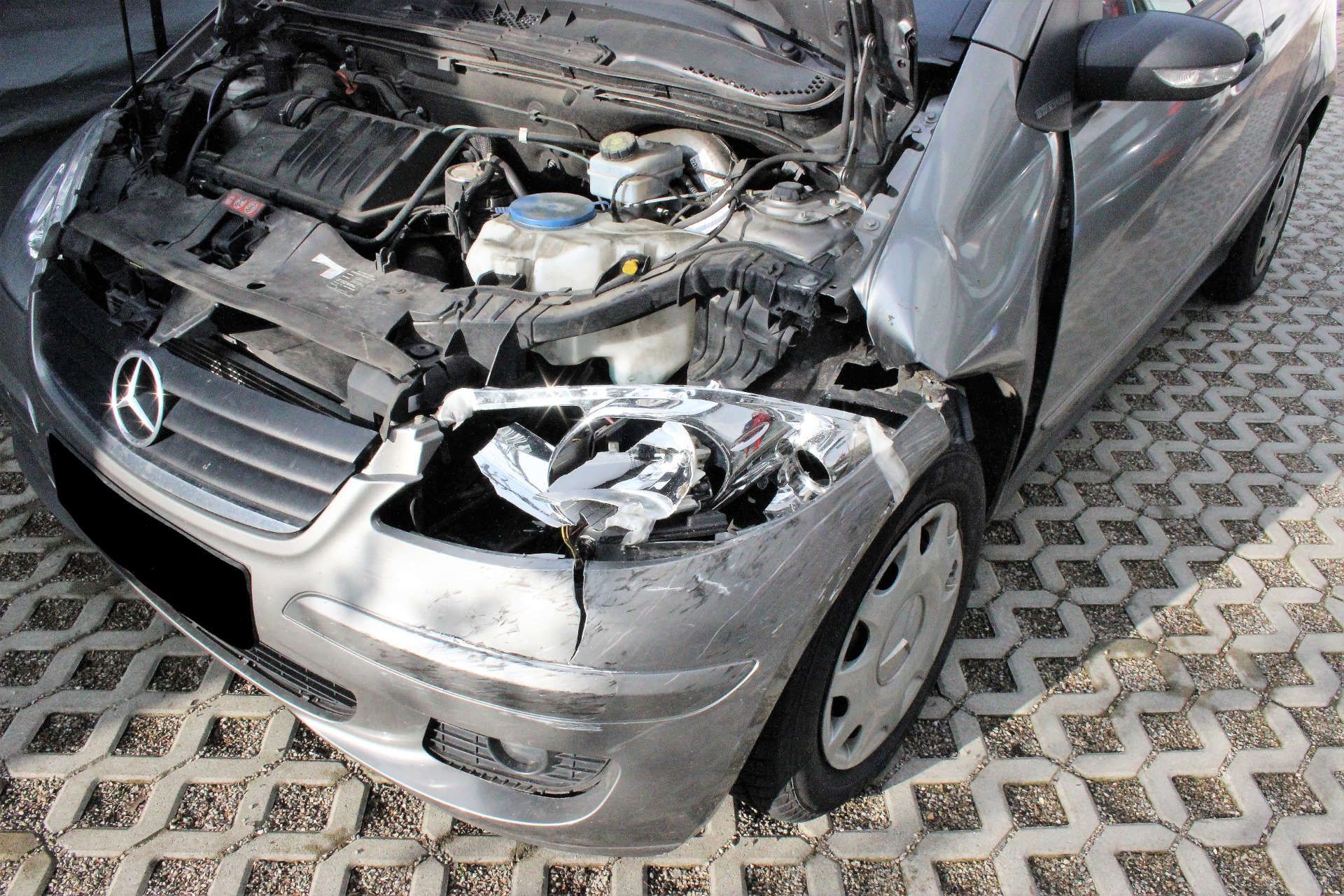 Silberner Mercedes mit geöffneter Motorhaube und stark beschädigtem vorderem rechten Kotflügel und Scheinwerfer.