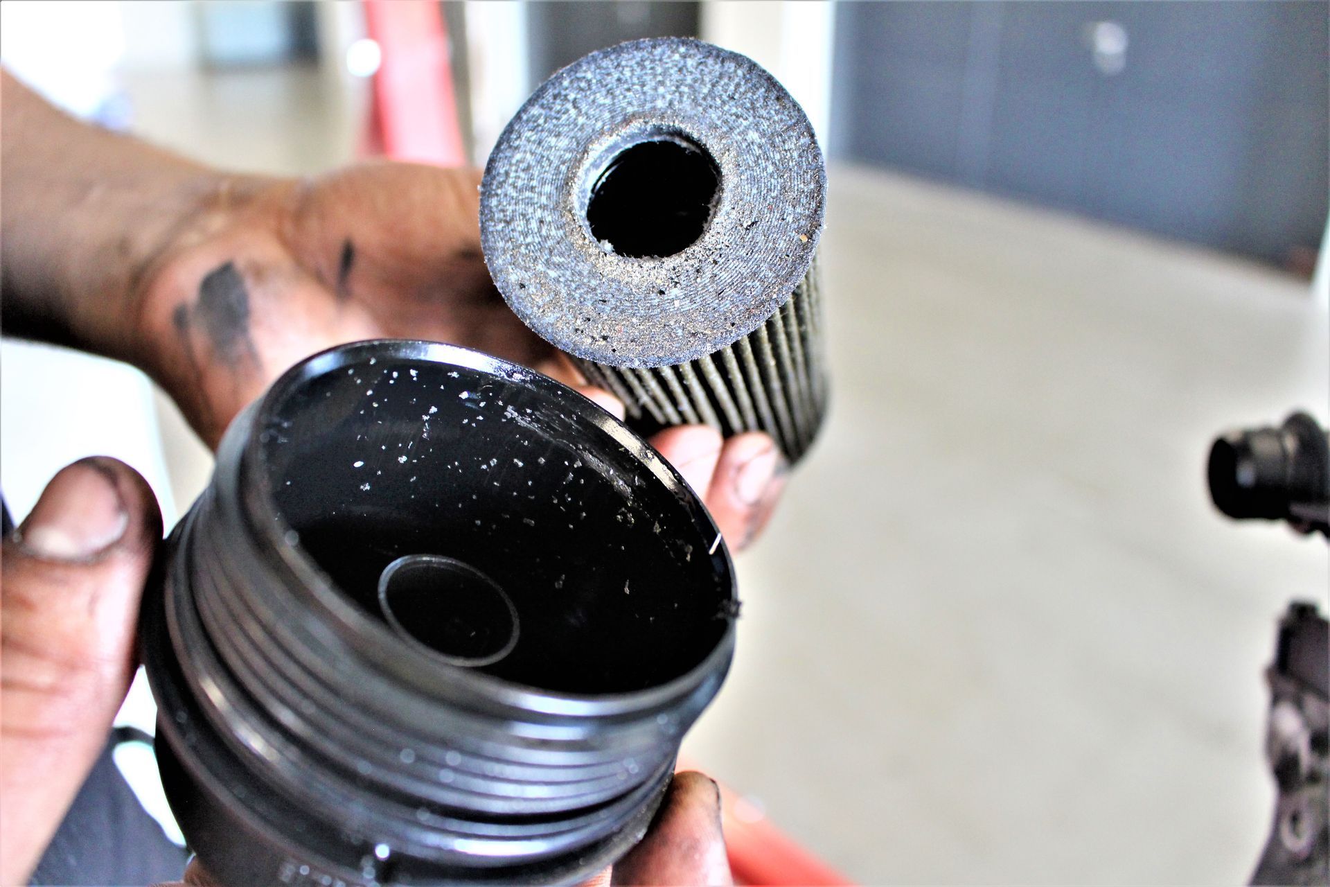 Ein Mechaniker zeigt einen gebrauchten Ölfilter und die Ölfilterpatrone.