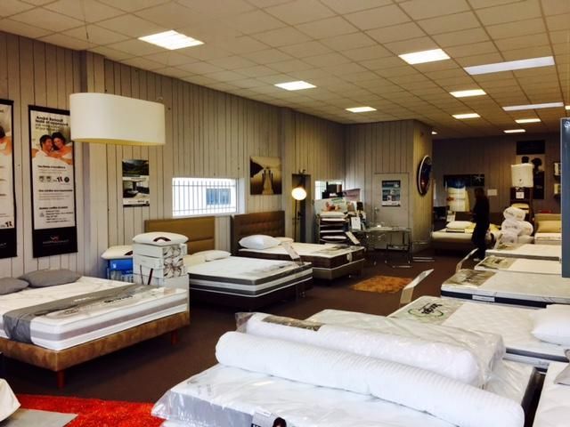 Intérieur d'un magasin de matelas avec différents lits et présentoirs, tons neutres, bon éclairage