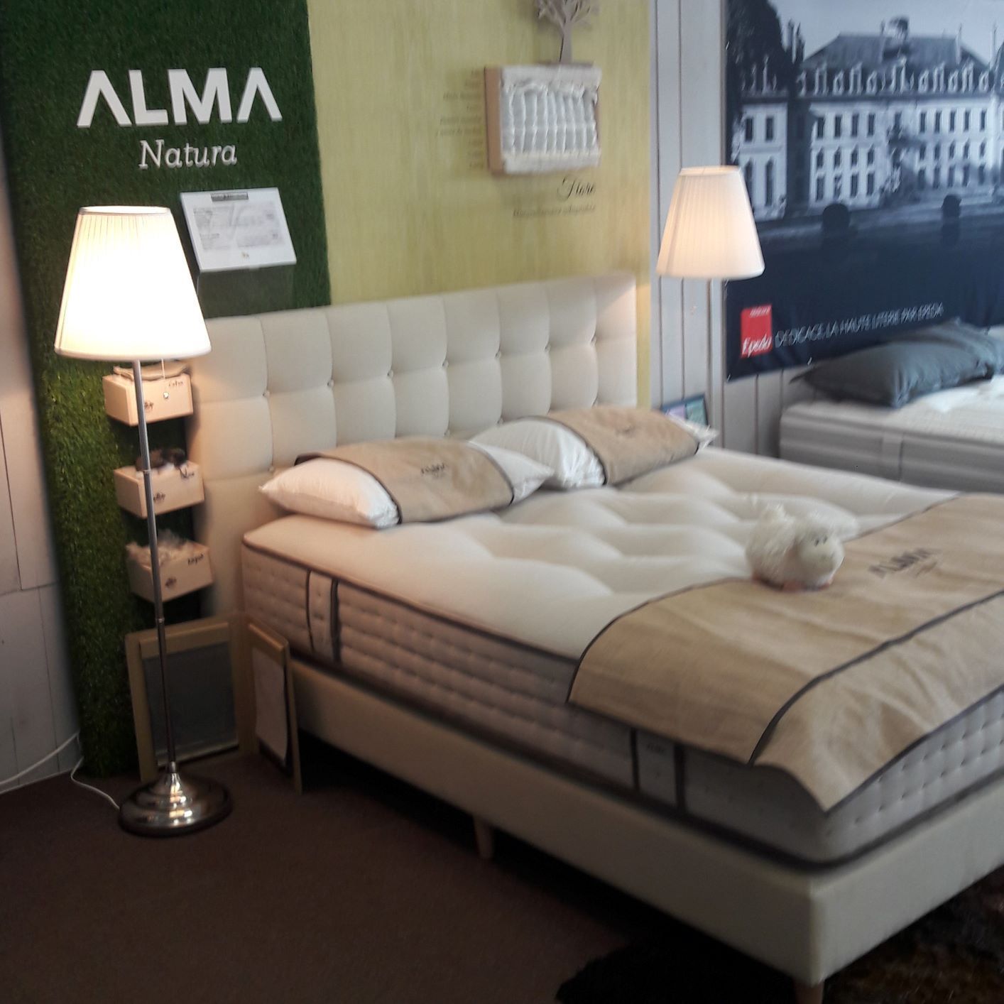 Présentation d'un lit en magasin, avec lampes, oreillers et tête de lit