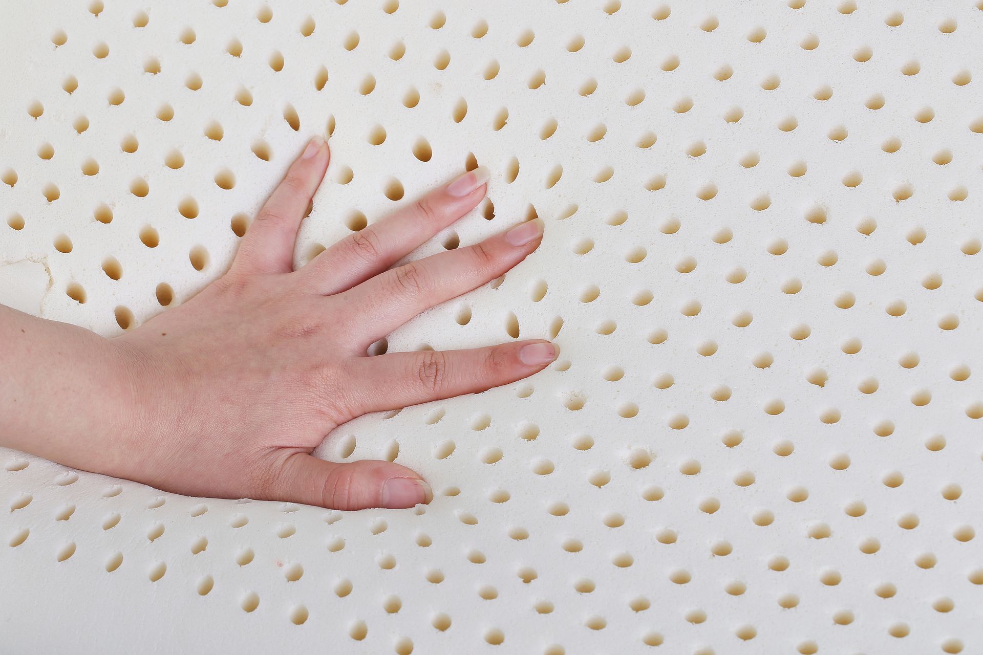 Main posée sur un matelas en latex avec ses alvéoles