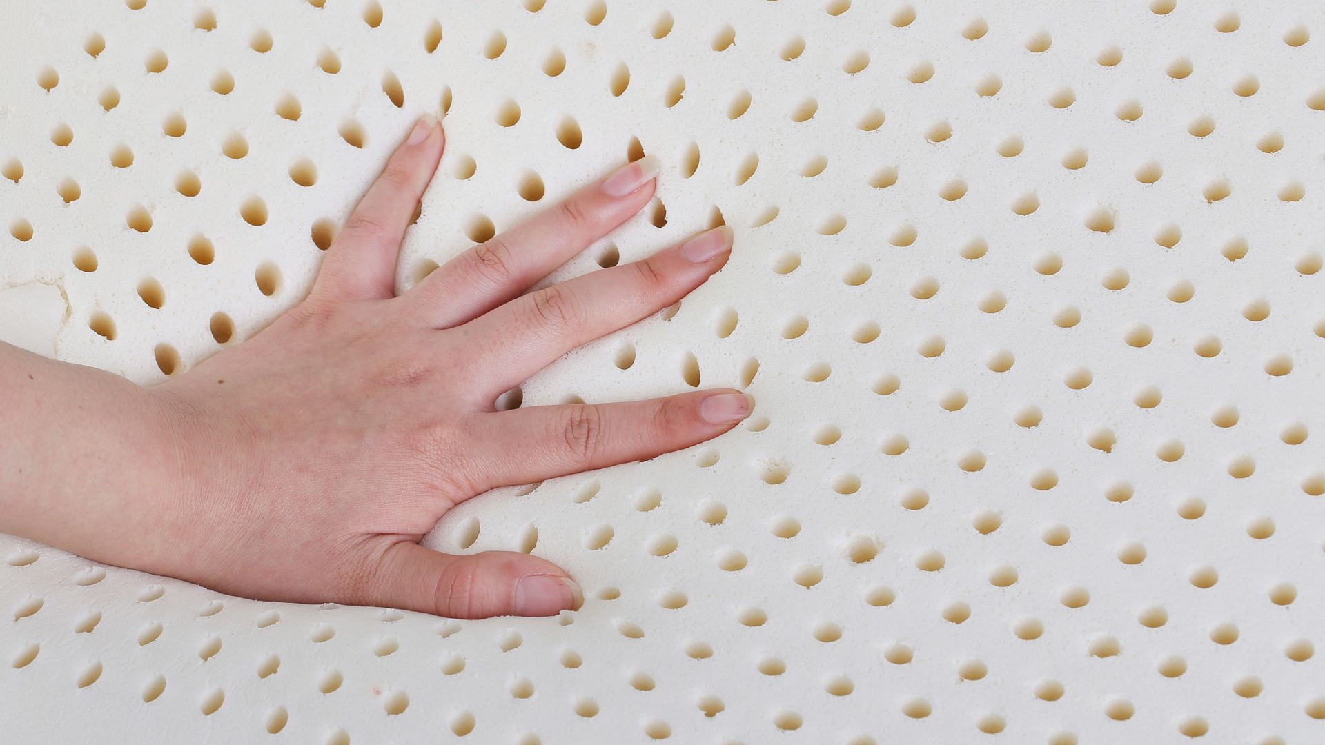 Main appuyée contre une mousse en latex pour matelas