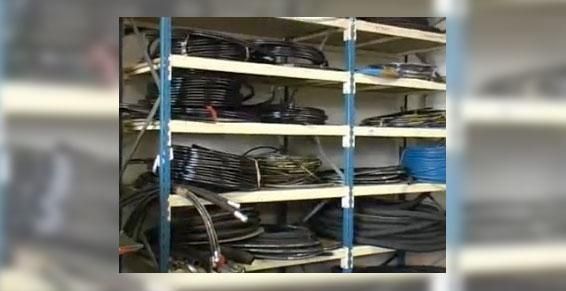 Étagère remplie de câbles noirs et bleus enroulés dans une pièce de stockage