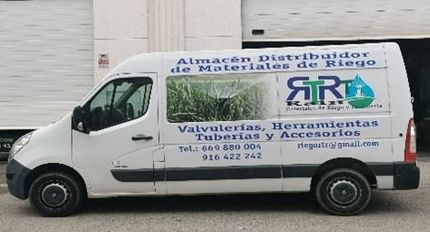 Una furgoneta blanca está estacionada delante de un almacén.