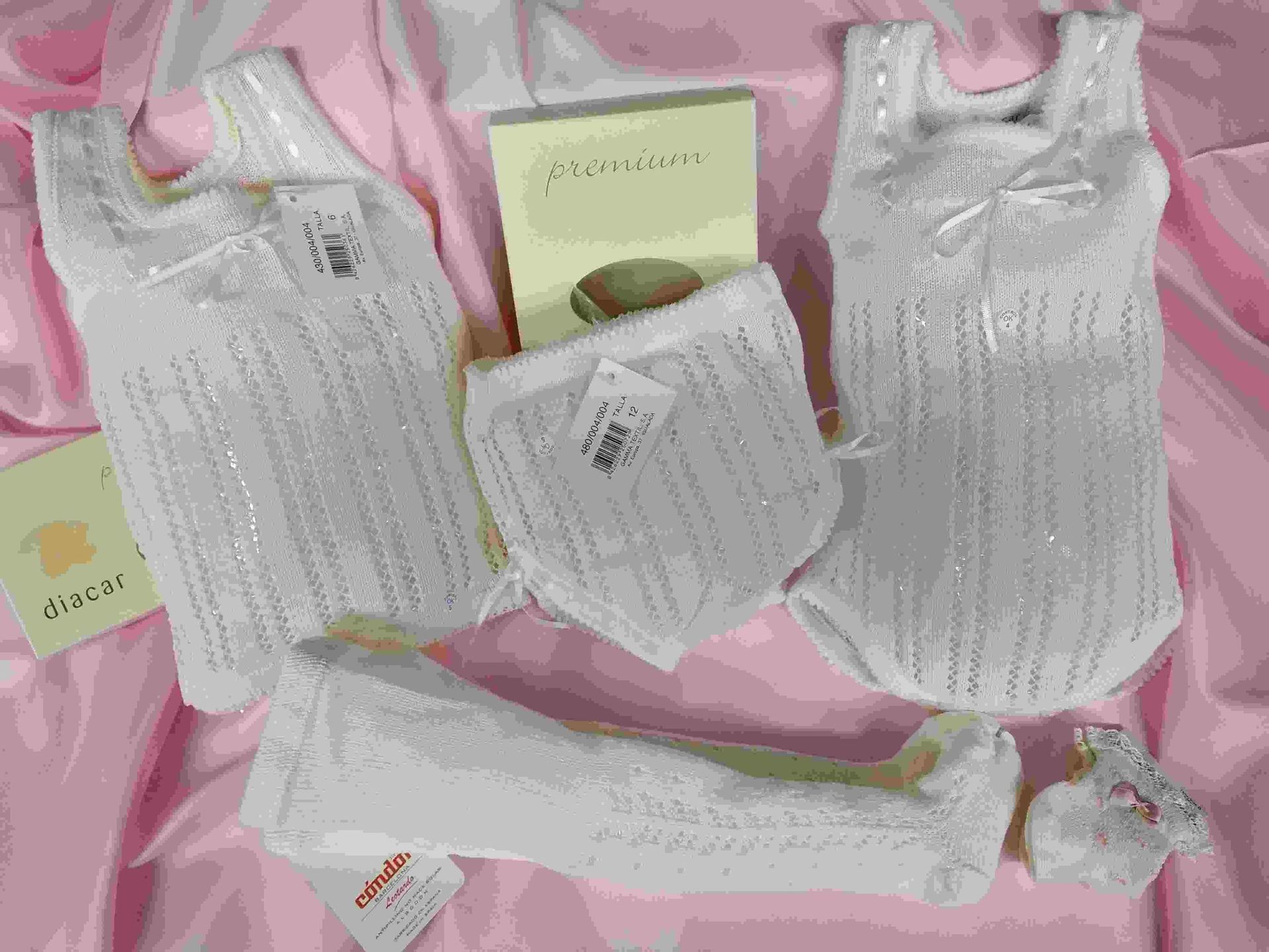 La ropa de un bebé está colocada sobre una tela rosa.