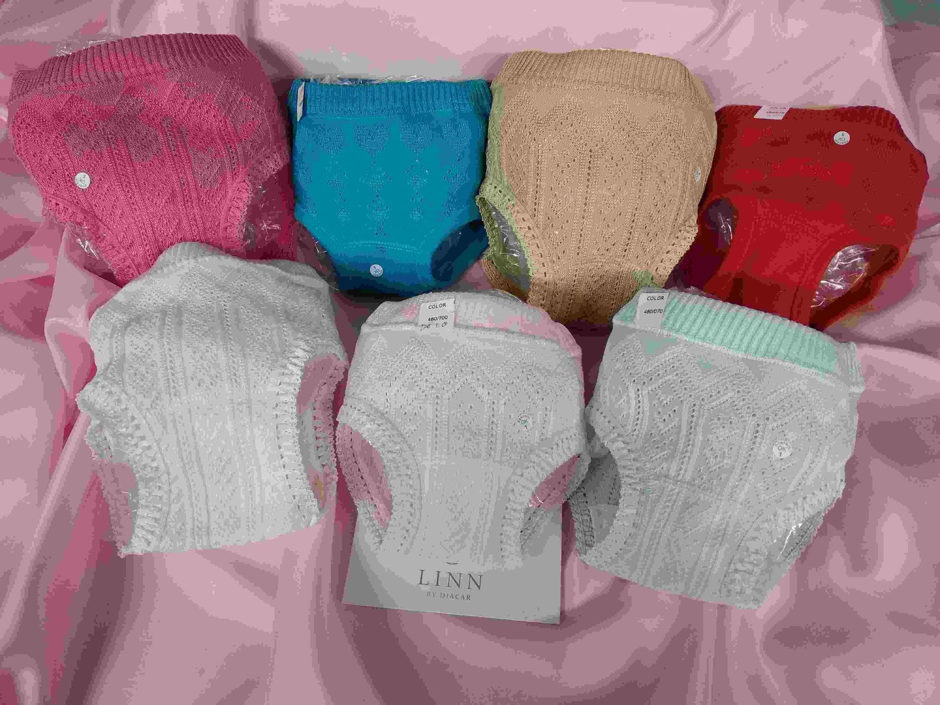 Un grupo de pañales están colocados encima de una tela rosa.