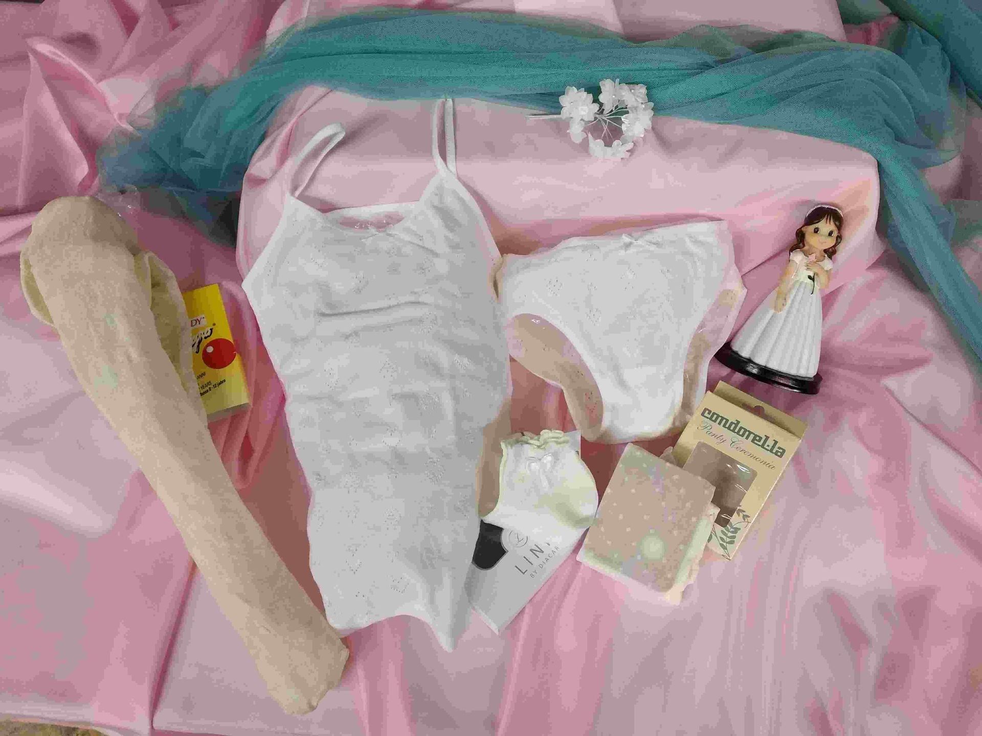 Una muñeca está sentada encima de una manta rosa al lado de una muñeca.