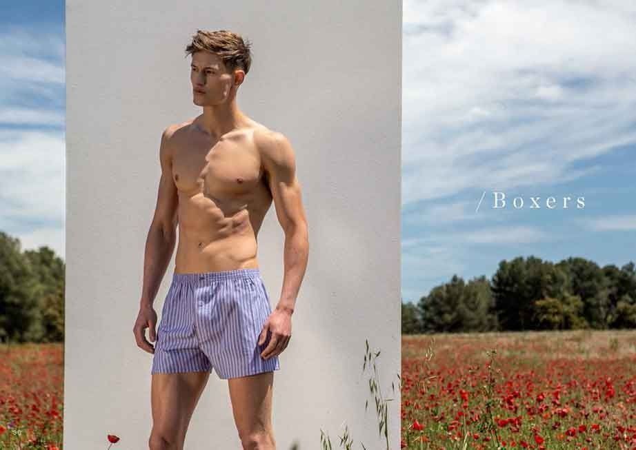 Un hombre sin camisa y en calzoncillos está parado en un campo de flores.