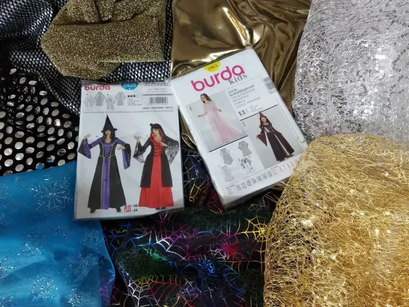 Una caja de patrones de costura Burda está encima de una pila de tela.