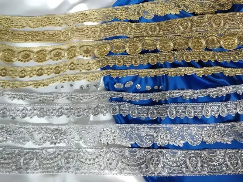 Un manojo de encaje dorado y plateado sobre una tela azul y blanca.