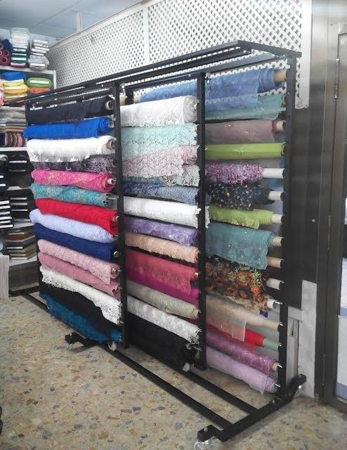 Un estante lleno de rollos de tela en una tienda.