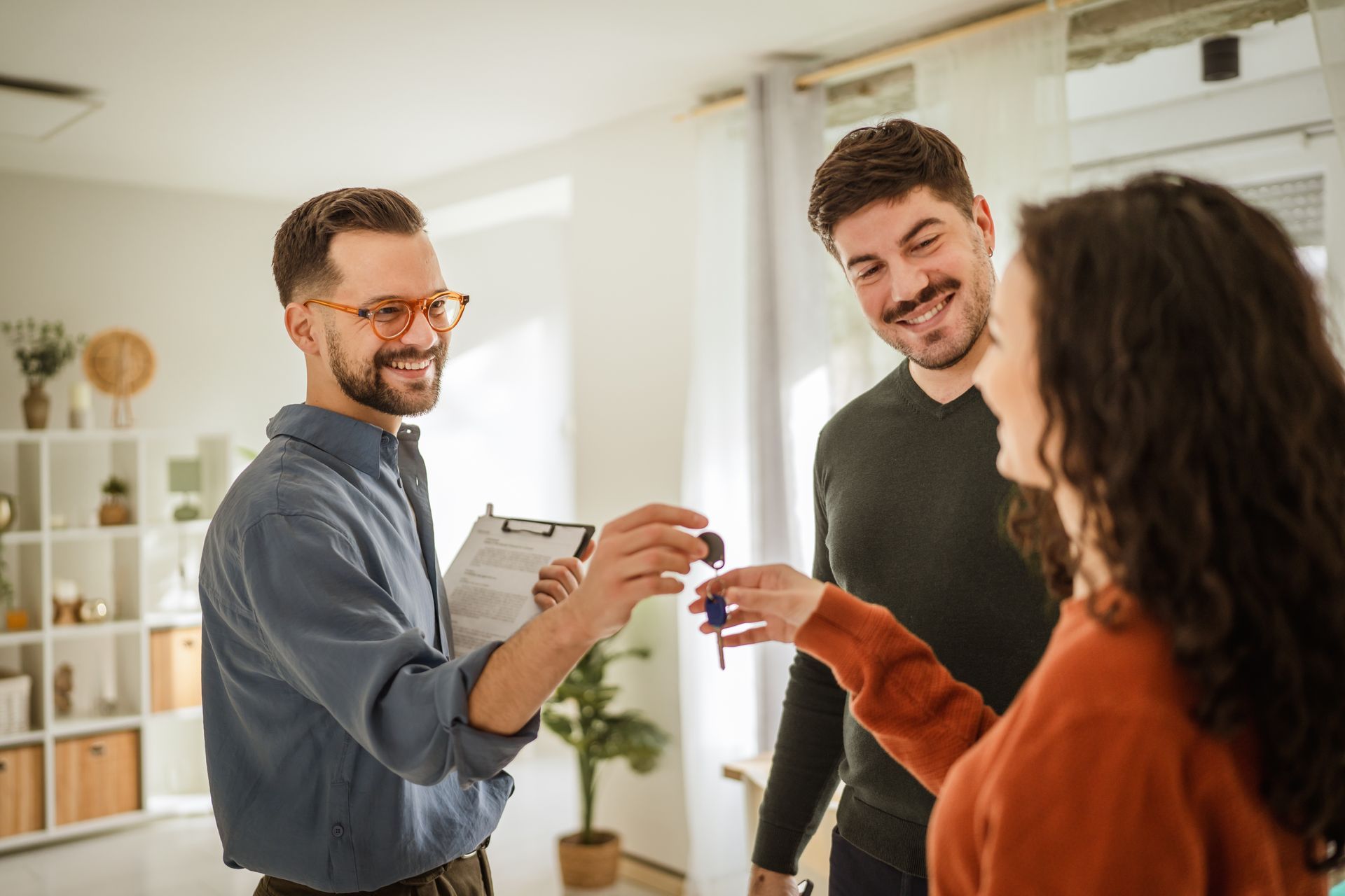 Trois collègues sourient et trinquent dans une salle de pause lumineuse.