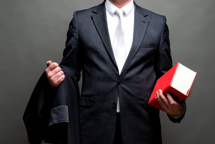 Homme d'affaires en costume sombre tenant un livre et une veste.