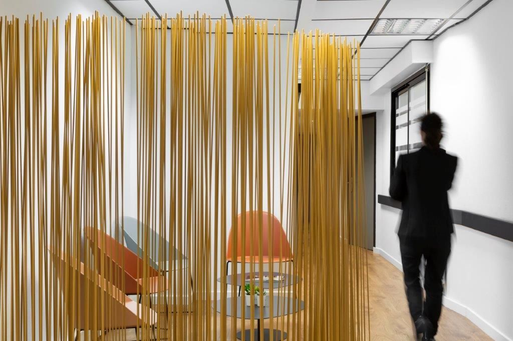 Bureau moderne avec cloison, table ronde et chaises, et une personne qui passe sur la droite