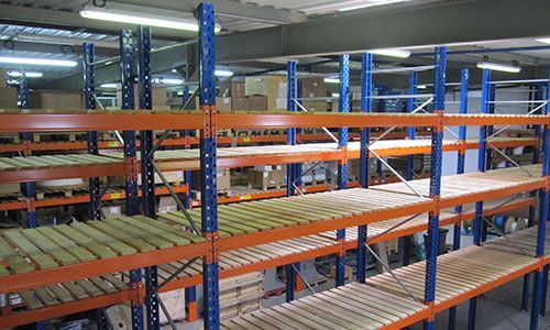 Étagères industrielles orange et bleues avec des planches de bois dans un intérieur d'entrepôt