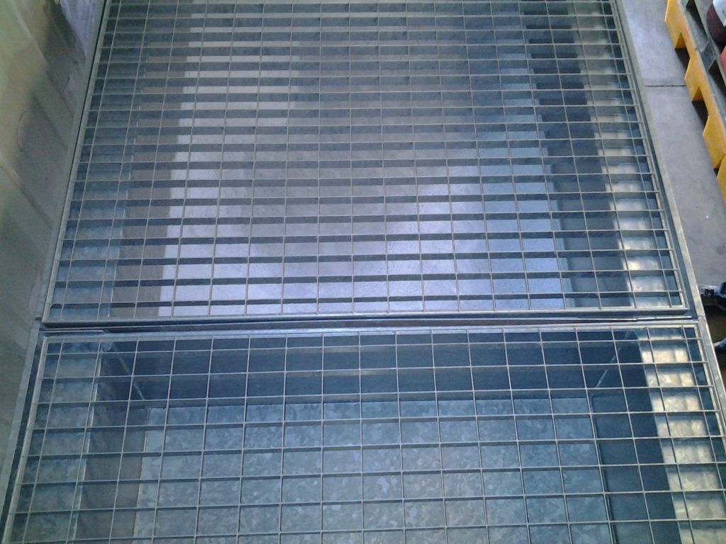 Grille industrielle métallique ou marches d'escalier vues de dessus, avec des rambardes jaunes des deux côtés.