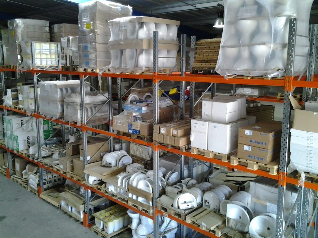 Des étagères de stockage remplies de marchandises ménagères emballées et conditionnées se trouvent dans une allée d'entrepôt.