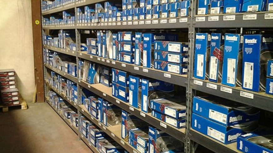 Une allée de magasin avec des étagères remplies de pièces de quincaillerie emballées dans des boîtes bleues et blanches.