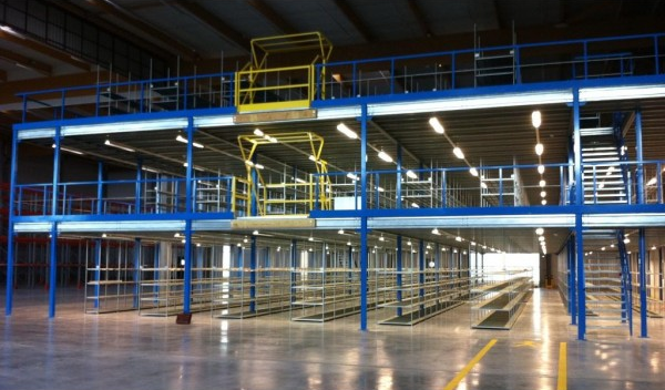 Intérieur d'entrepôt vide avec passerelles en acier bleu et rambardes jaunes sous une lumière vive zénithale