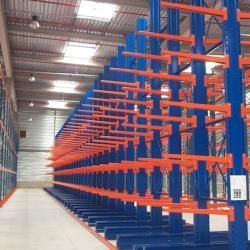 Allée d'entrepôt vide avec de hauts rayonnages industriels bleus et orange