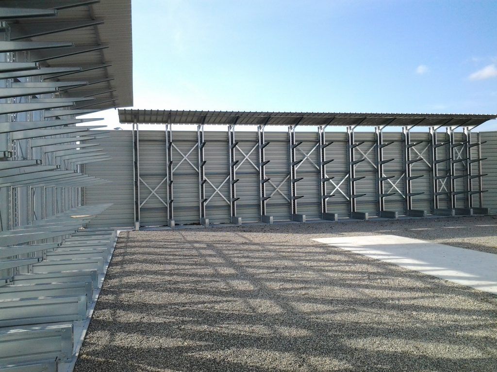 Vue extérieure d'un bâtiment moderne en béton avec une cour en gravier et un ciel bleu
