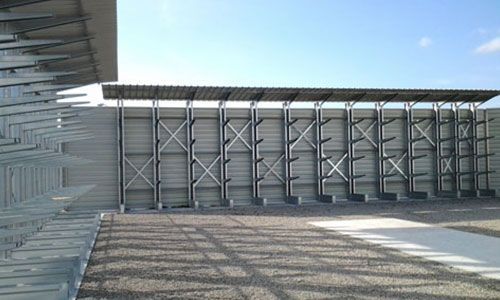 Cour industrielle vide avec des panneaux muraux métalliques et un toit en tôle ondulée sous un ciel dégagé
