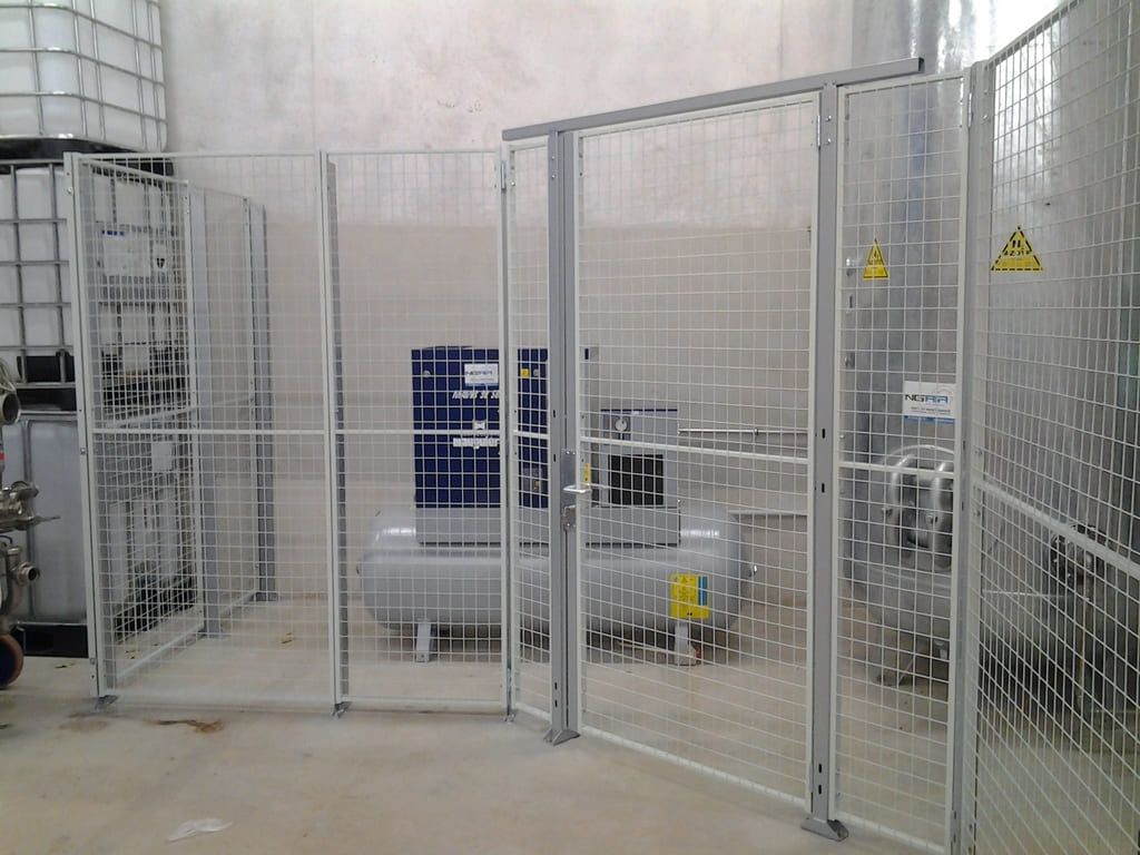Équipements industriels derrière une clôture de sécurité blanche dans une salle blanche d'usine