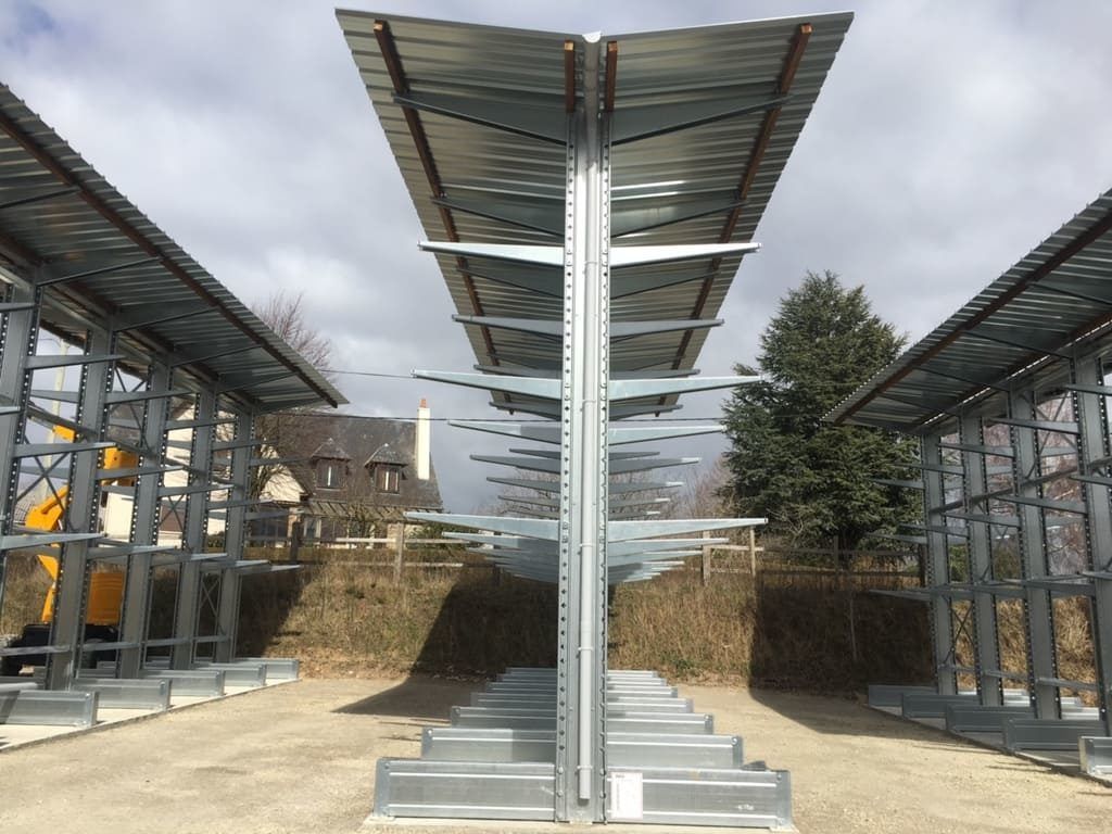 Allée extérieure moderne avec structures métalliques et colonnes de soutien centrales sous un ciel nuageux
