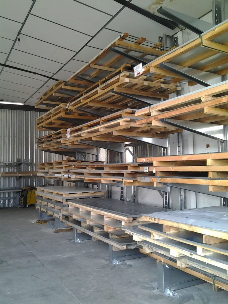 Entrepôt industriel avec de longues étagères en bois empilées sur des supports métalliques sous un plafond ondulé