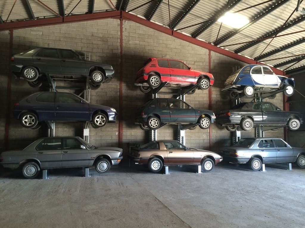 Neuf petites voitures exposées sur des étagères murales dans une pièce ressemblant à un garage.