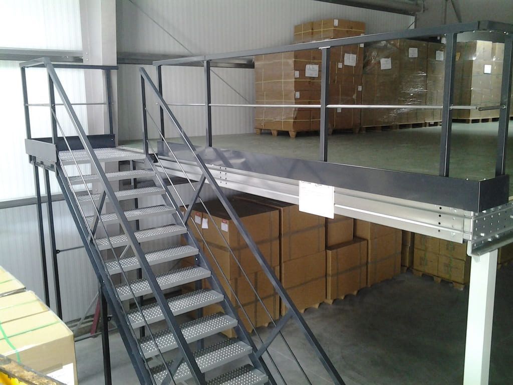 Mezzanine intérieure d'entrepôt avec escalier métallique, rambardes et cartons empilés