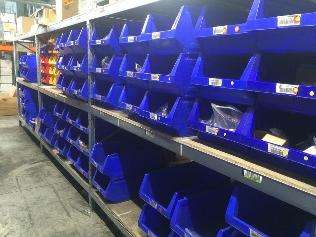 Bacs de rangement en plastique bleu sur des étagères d'entrepôt dans une allée industrielle