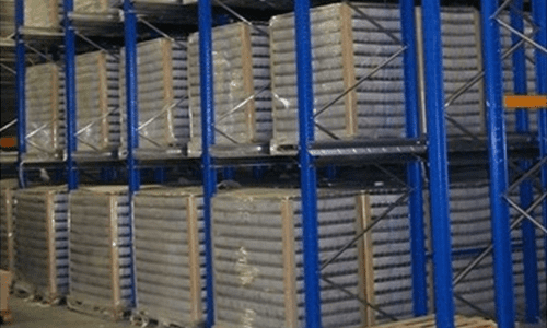 Rayonnages bleus d'entrepôt remplis de rangées de grands conteneurs cylindriques blancs dans une zone de stockage industrielle