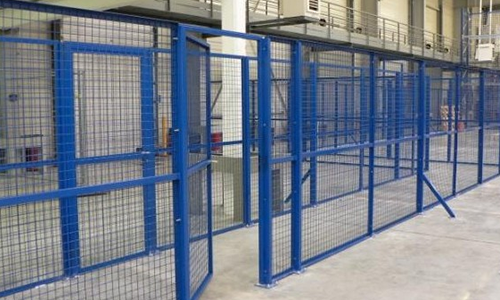 Cages de sécurité en treillis métallique bleu dans un couloir d'entrepôt industriel.