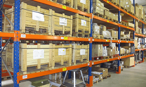 Des étagères d'entrepôt remplies de cartons et de caisses sur des rayonnages métalliques orange.