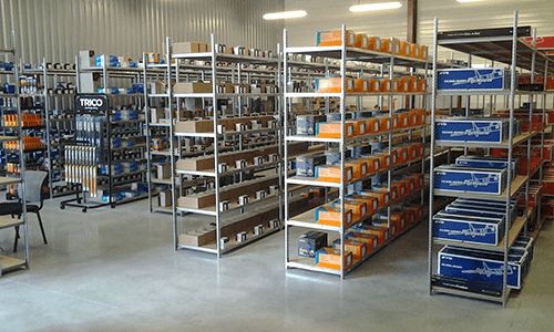 Entrepôt industriel avec rayonnages métalliques remplis de bacs et de boîtes de rangement orange et bleus