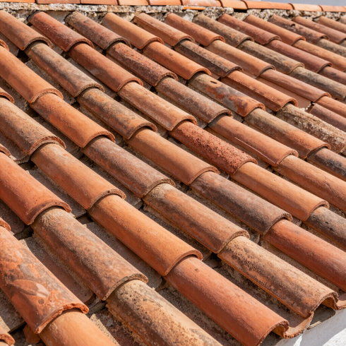 Primer plano de tejas de terracota desgastadas dispuestas en filas diagonales.