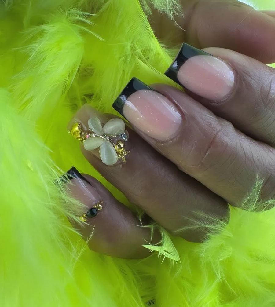 Primer plano de una mano con uñas color nude y detalles de joyas que sostiene plumas de color verde lima brillante.