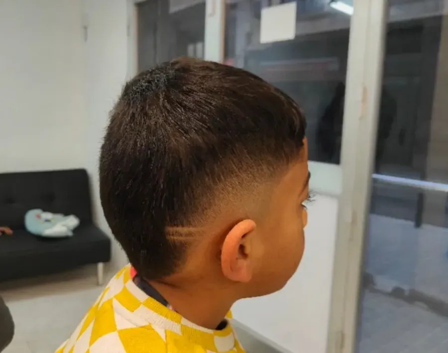 Un niño con el pelo corto mira por la ventana de una habitación luminosa.