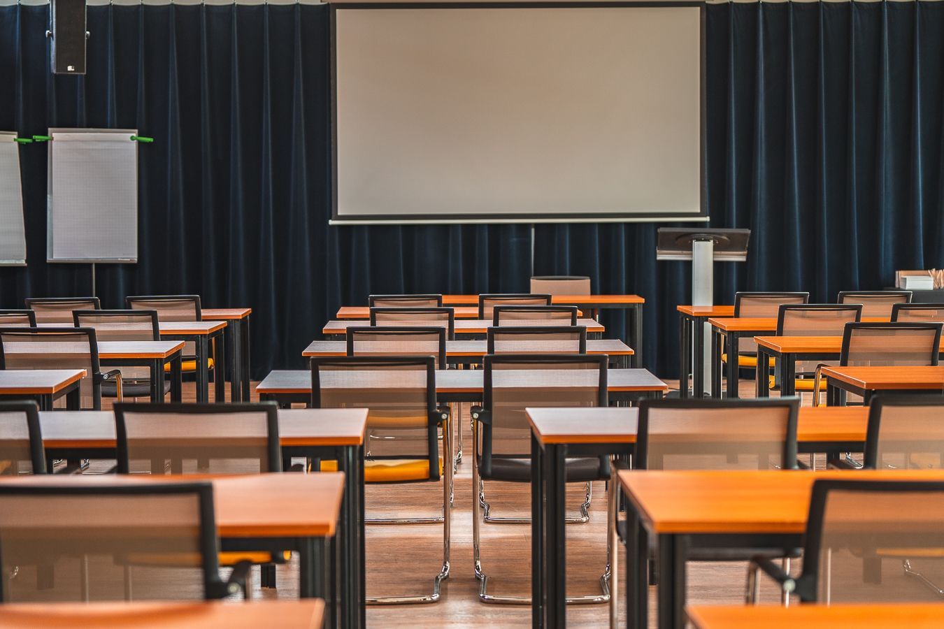 Een conferentieruimte met tafels en stoelen en een projectiescherm