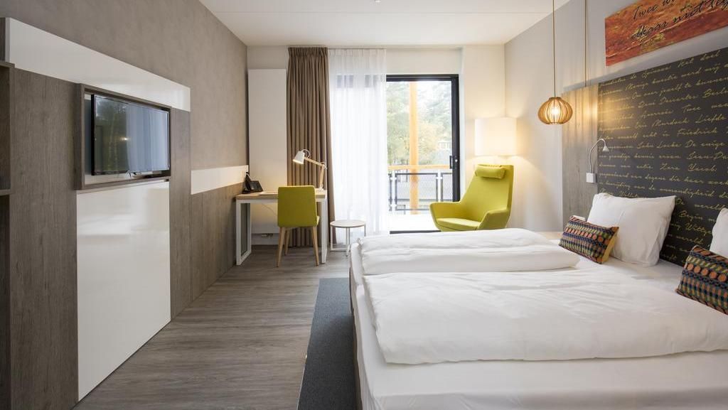 A hotel room with two beds , a chair , a desk and a television.