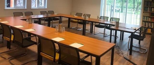 Een vergaderruimte met tafels en stoelen die klaar staan voor een vergadering.