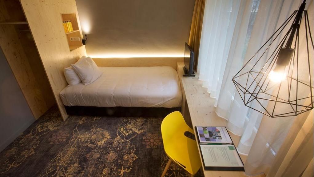 A hotel room with a bed , desk and chair.