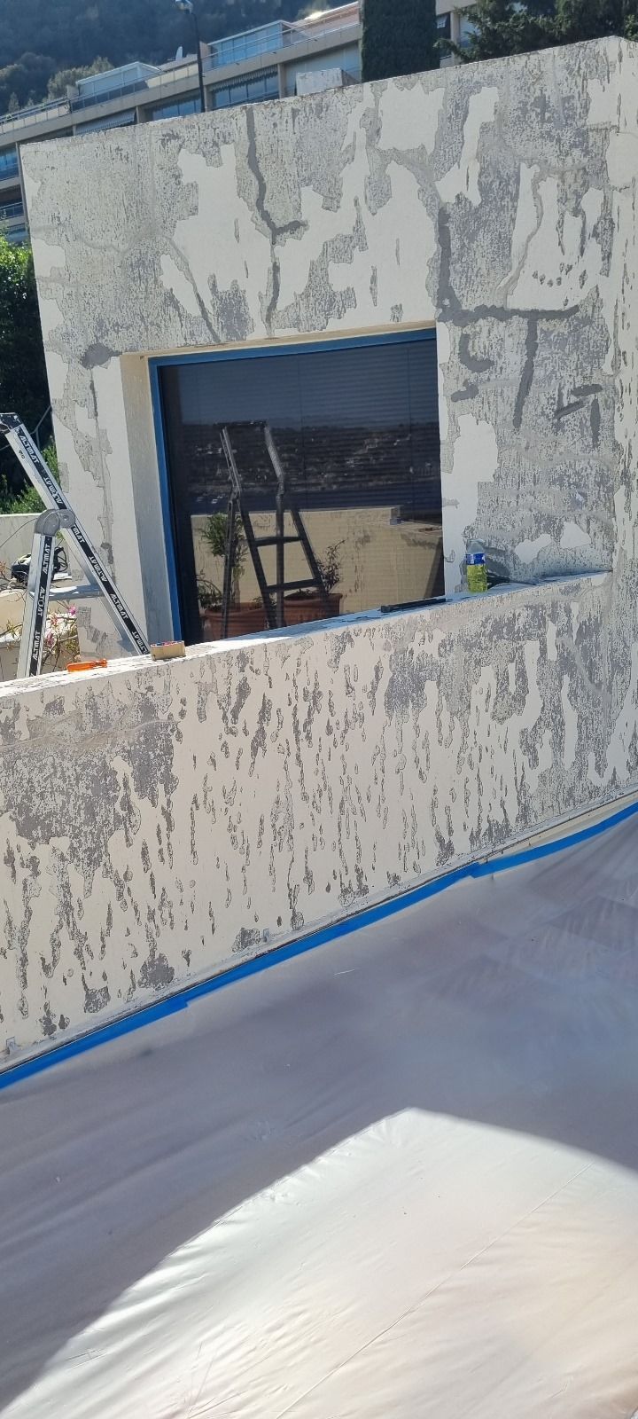 Un mur blanc avec une fenêtre est en train d'être peint.