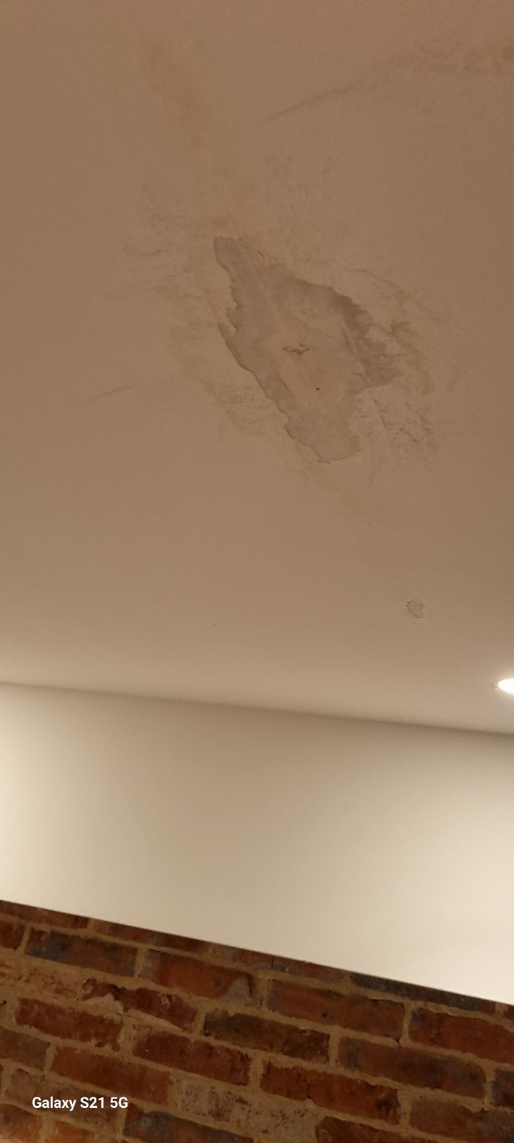 Un plafond blanc avec un mur de briques en arrière-plan.