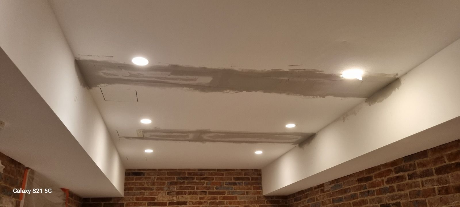 Une pièce avec un mur de briques et un plafond blanc.