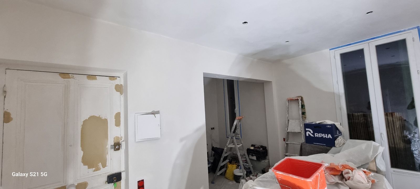 Un salon en construction avec une échelle et un pot de peinture.