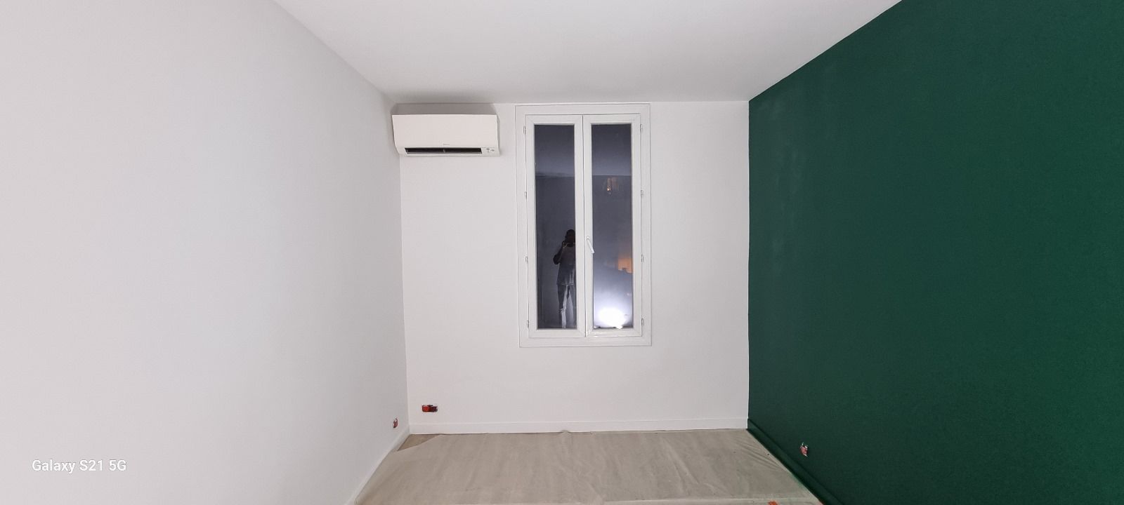 Une pièce vide avec un mur vert et une fenêtre.