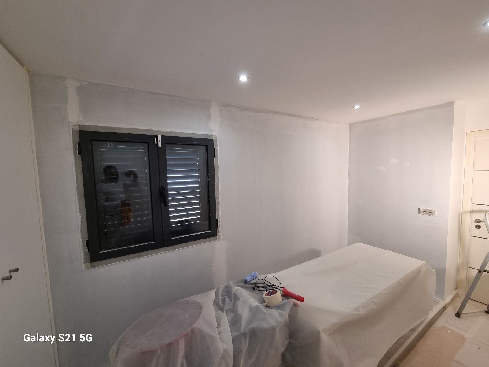 Une chambre est en train d'être peinte avec un lit et une fenêtre.